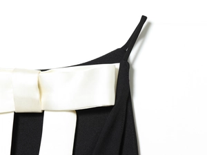 Détail d'un grand nœud en satin blanc sur une robe dos nu noire pour femme