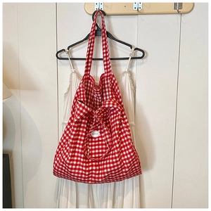 Detail of red and white checkered canvas tote bag with good label hanging on wall hook