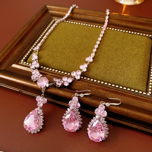 Dettaglio di parure con collana e orecchini in zircone rosa su velluto verde scuro