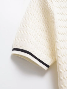 Close-up of white cable-knit texture with contrast black stripes on the cuff