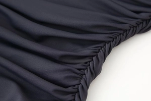 Gros plan sur la texture froncée du tissu jersey gris foncé d'une robe de soirée chic