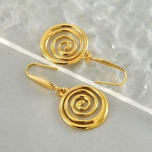 Macro detail of polished gold spiral drop earrings on a premium silk textured background