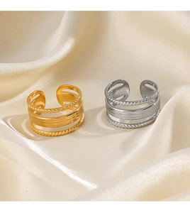Detail of 18K gold and silver layered open rings on a smooth beige satin background
