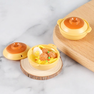 Macro detail of miniature seafood clay pot noodles with realistic egg and meatballs