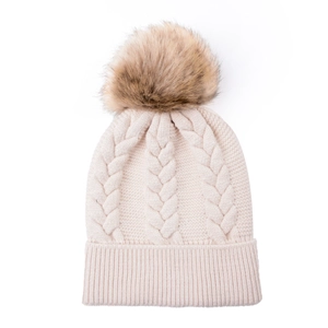 Close-up of cable knit texture and fluffy faux fur pom-pom on the beige winter beanie