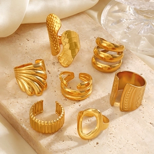 Set of seven chunky geometric gold titanium steel rings on a marble display stand