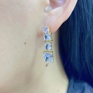 Close-up of gold dangle earrings with four geometric cubic zirconia stones on model