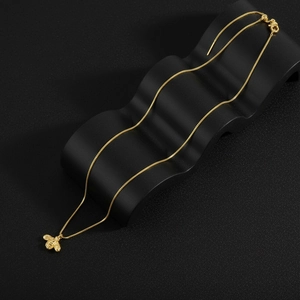 Detail of 18K gold plated bee pendant showing intricate textures on a black wavy base