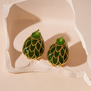 Gros plan sur des boucles d'oreilles vintage vert émeraude avec texture dorée et gemmes