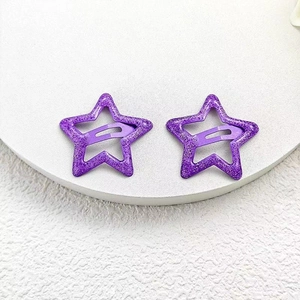Detail of two purple glitter star snap clips on a white tray for girls' hair styling