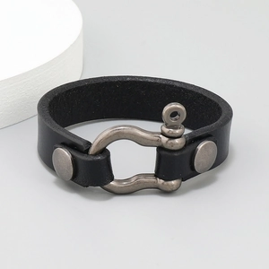 Detail of black top-grain leather bracelet featuring a bronze horseshoe buckle clasp