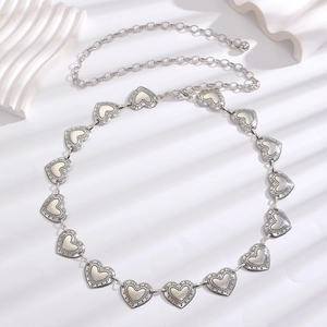 Close-up of vintage silver heart-shaped metal chain belt with lobster clasp and engravings