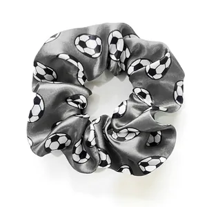 Macro view of grey satin scrunchie featuring a detailed black and white football pattern
