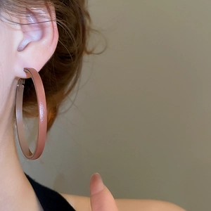 Close-up of geometric round leather hoop earrings in earthy pink on a model