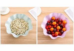 Close-up of wavy petal edge plastic fruit bowls holding nuts and grapes on a wooden table