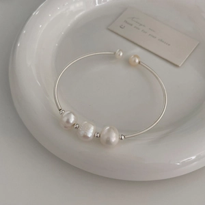 Detailed close-up of a silver spiral cuff bracelet featuring three freshwater pearls