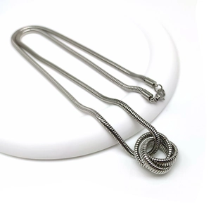 Detail of silver snake chain necklace featuring a unique coiled knot pendant design