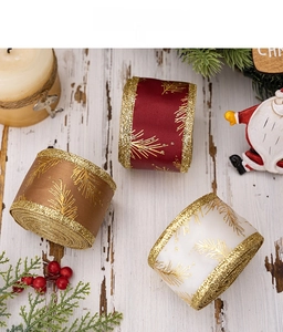 Macro view of Christmas ribbons with gold pine needle prints and glittered edges on wood