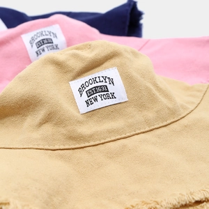 Dettaglio di cappelli bucket in tela multicolore con bordi a frange e etichette