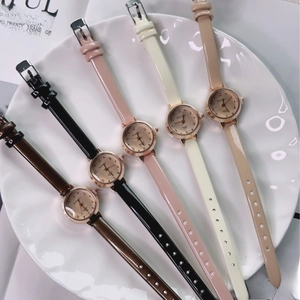 Flat lay of five minimalist women's quartz watches with leather straps on ceramic plate