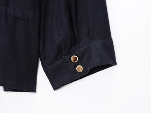 Detail of dark linen jacket cuff with two gold round metal buttons and textured fabric