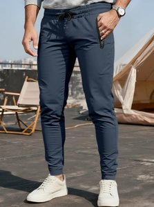 Detail of dark blue joggers showing elastic drawstring waist and hidden zipper pockets