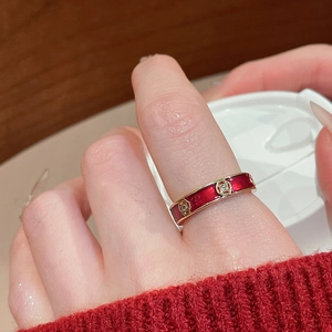 Close-up of red enamel ring with gold coin detail and crystal on a hand