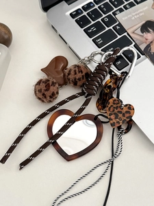 Detail of leopard print heart mirror keychain with plush ball and woven strap decoration