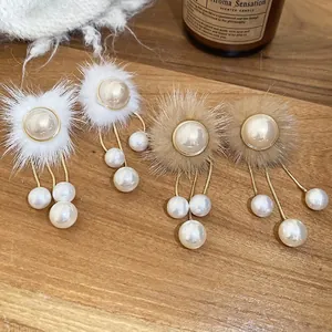 Winter style faux fur pompom earrings with elegant long pearl tassels on a wooden tray