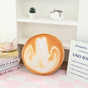 Detailed latte art plush cushion styled in a cozy home setting with books and teacups