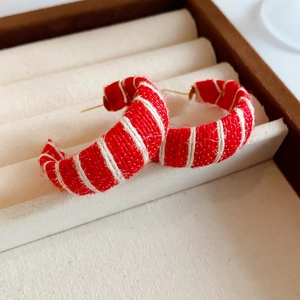 Macro shot of red and white woven fabric texture on C-shaped stud earrings detail