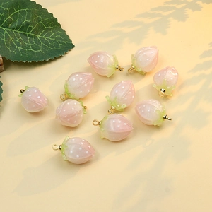 Macro shot of 10 pink strawberry pendants with gold rings for DIY jewelry making