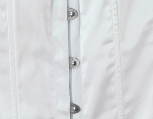 Détail macro de trois rangées d'agrafes métalliques argentées sur un haut corset en satin blanc