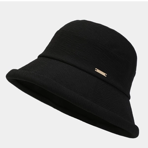 Chapeau bob en maille noire pour femme avec logo en métal doré sur fond gris épuré