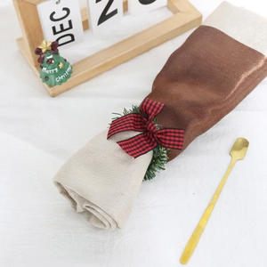 Close-up of pine needle wreath napkin ring with red plaid bow for Christmas table decor