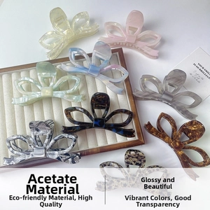 Dettaglio macro di pinze per capelli in acetato con texture marmorizzata e fiocco 3D