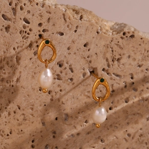 Detail of gold drop earrings featuring a freshwater pearl and green zircon accent