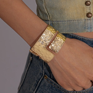 Detail of a hammered gold open cuff bracelet with an irregular geometric texture design