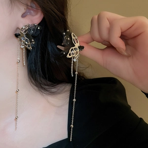 Close-up of black butterfly tassel earrings with silver needles on a model's ear