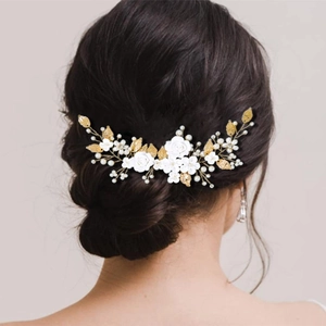 Elegant bridal hairpiece featuring white clay flowers and golden leaves on a model