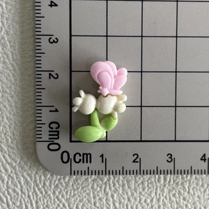 Accessoire en résine papillon rose sur fleur blanche avec règle montrant 2cm de haut
