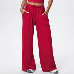 Detail of red wide-leg trousers with drawstring waist and soft draped fabric texture