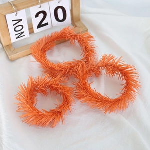 Three orange fluffy plush wreath hair rings on white fabric with wooden calendar decor