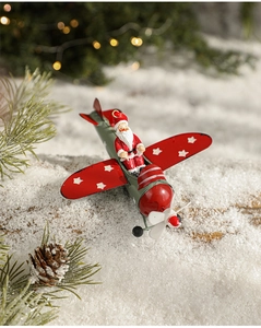 Macro detail of Santa Claus flying a vintage red and green metal airplane ornament