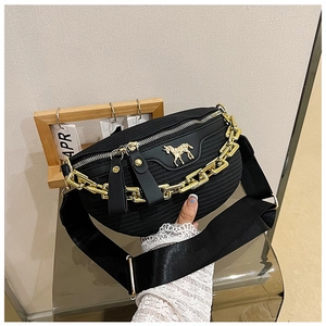 Detail of black woven chest bag featuring a gold horse emblem and chunky chain decoration