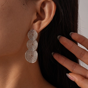 Close-up of geometric mesh hollow circular earrings in a refined metallic silver finish