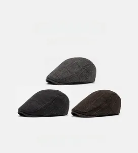 Detailed view of three herringbone tweed flat caps in grey, dark grey and brown tones