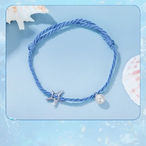Detail of blue woven rope bracelet with silver starfish charm and white pearl bead