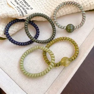 Colorful spiral phone cord hair ties with heart star pendants on a textured fabric surface