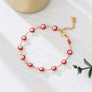 Close-up of golden evil eye bracelet with colorful enamel beads on a white textured cloth